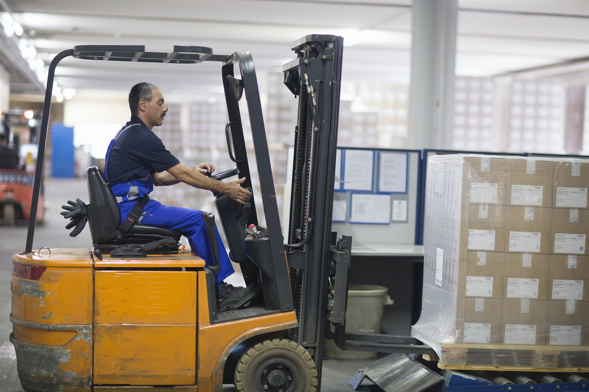 Mature man using forklift truck in factory