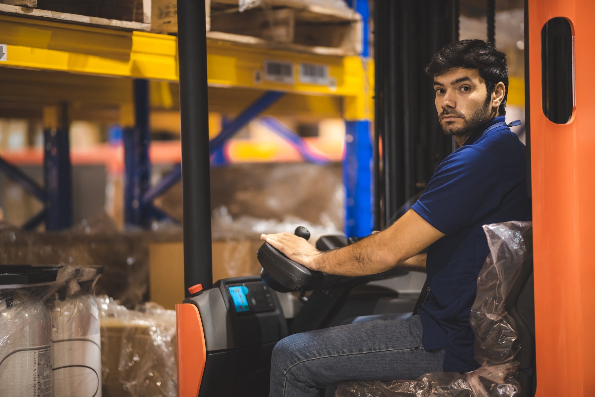 Young forklift driver sitting in vehicle in warehouse