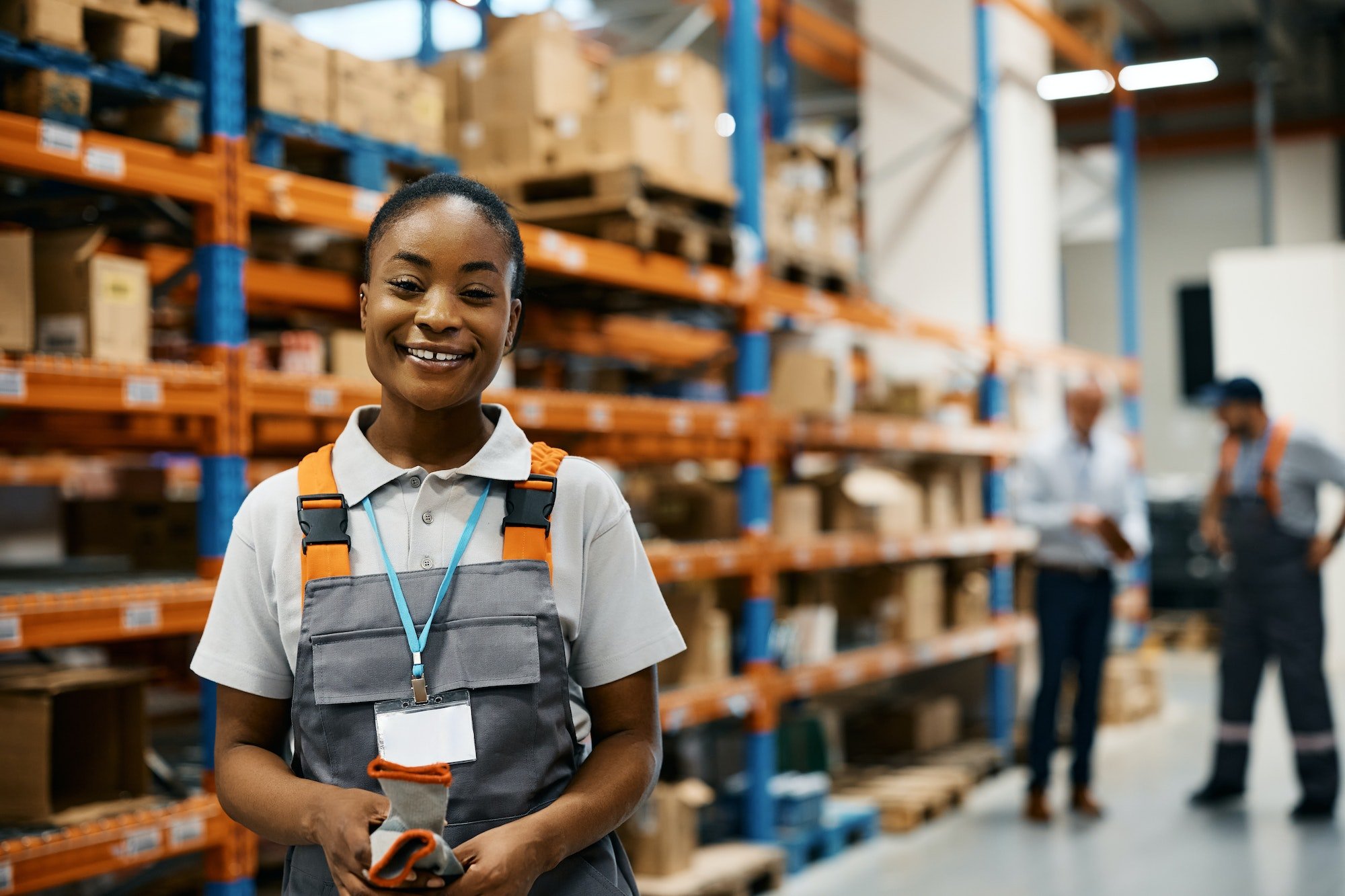 Happy black female worker at distribution warehouse looking at camera.