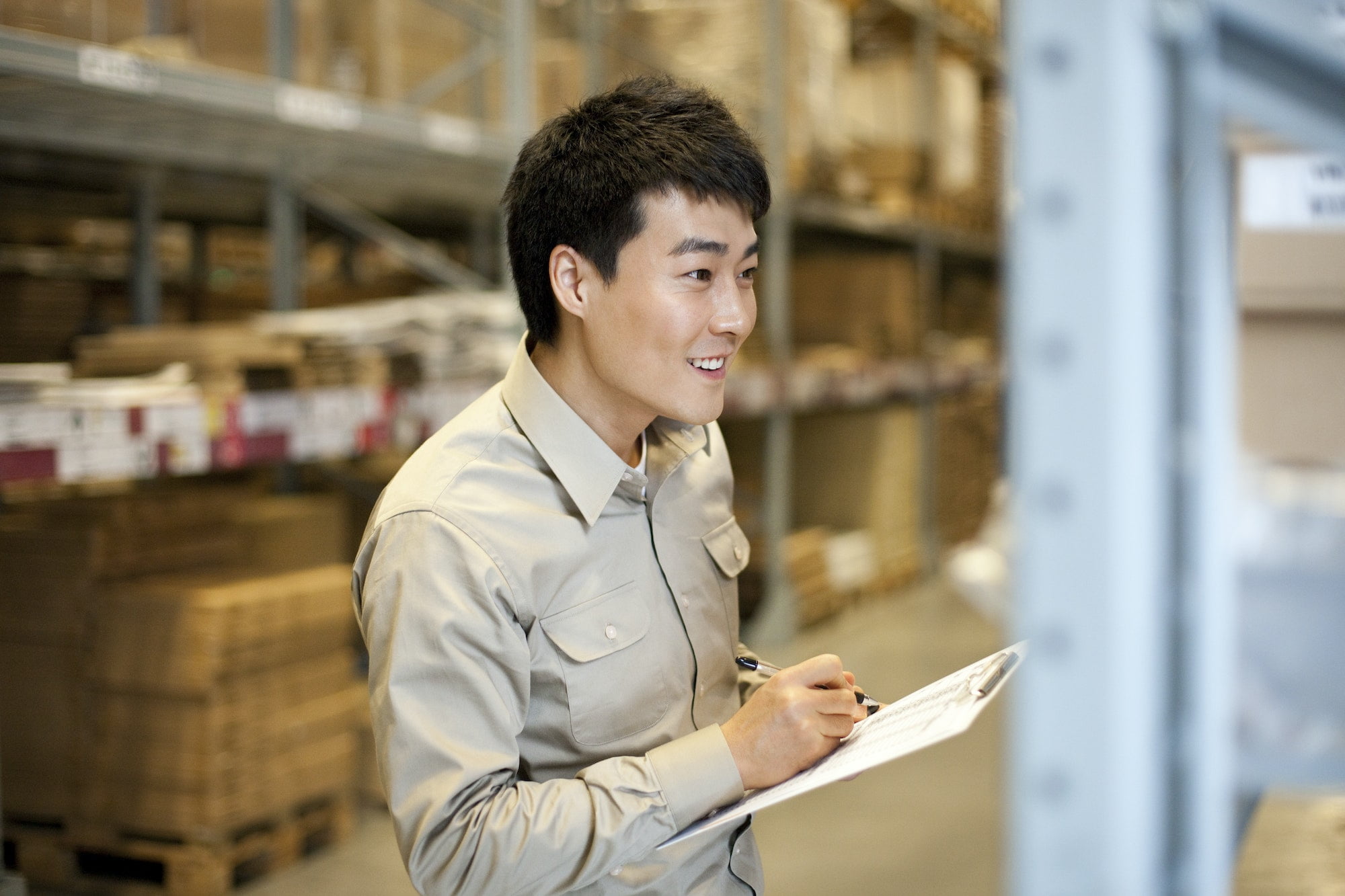 Male Chinese warehouse worker with clipboard