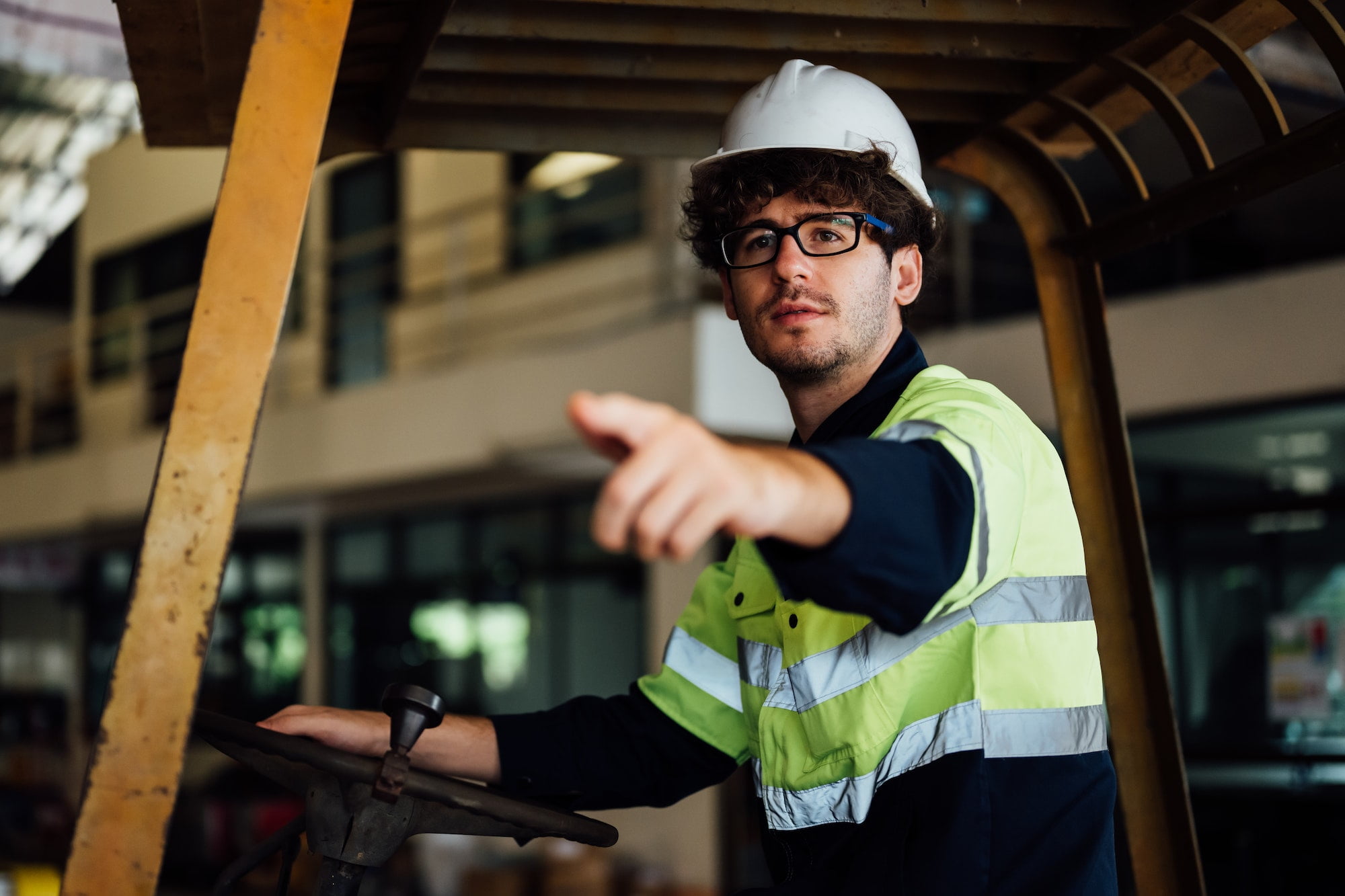 Male industrial engineer in white hard hat driving forklift