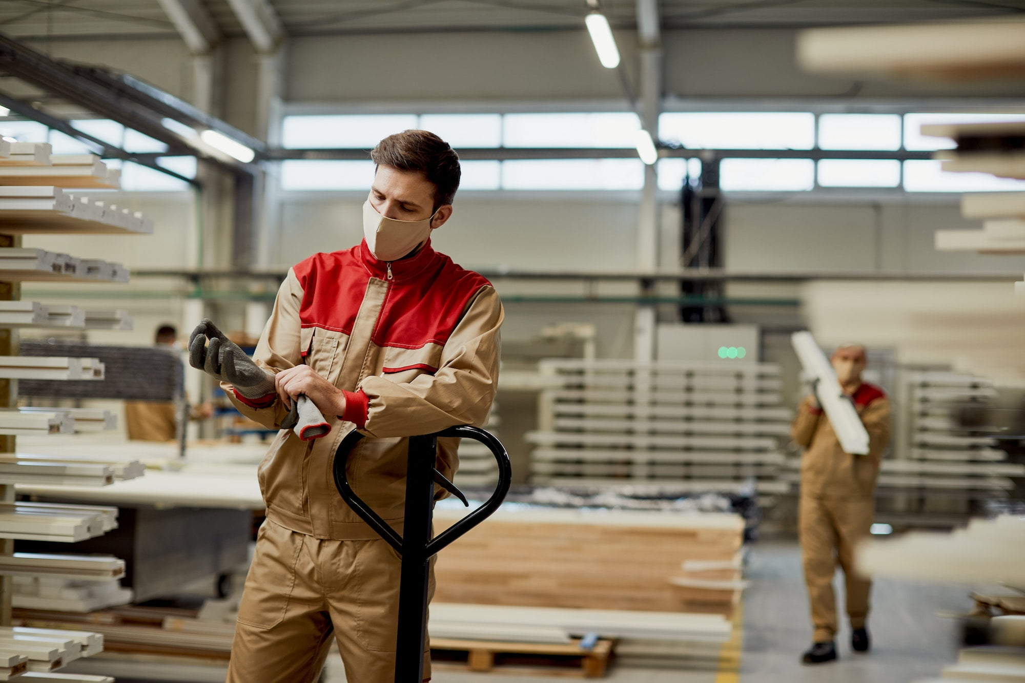 Manual worker using protective gloves while working at carpentry warehouse.